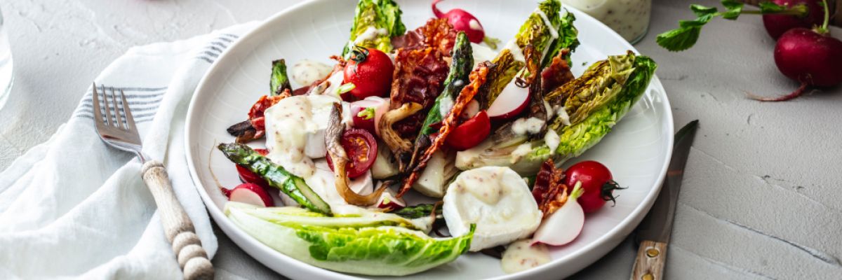 Salat mal anders genießen: Mit angebratenem Romanasalat und grünem Spargel. Herzhaft abgerundet wird er mit einem Kartoffel-Speck-Dressing ©KMG/die-kartoffel.de