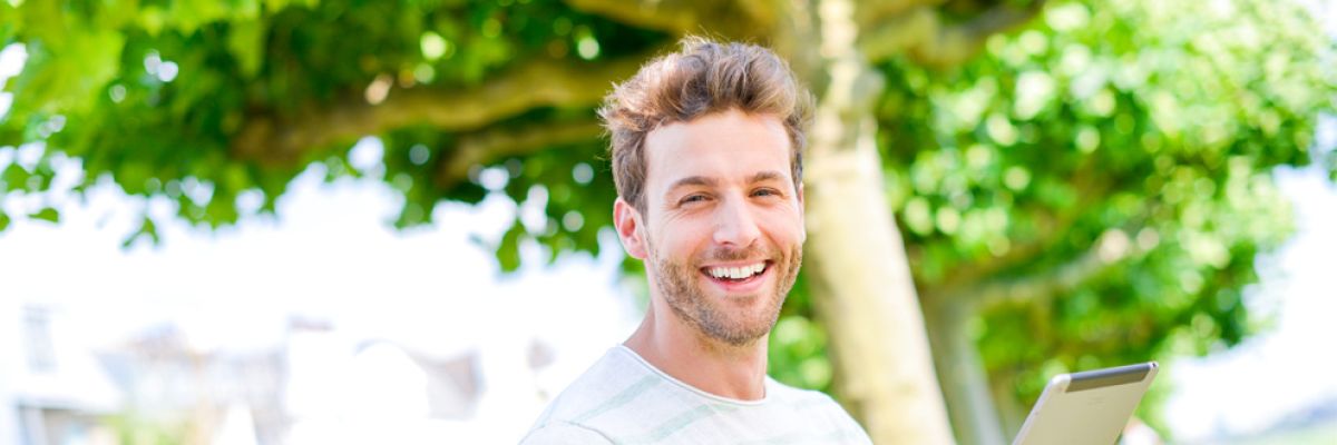 Mann draußen mit Notebook.