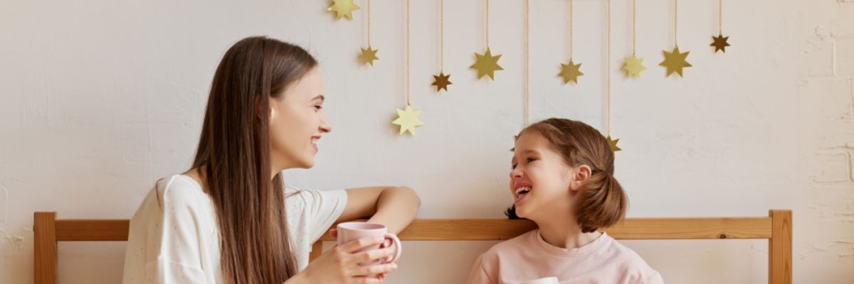 Hygge-Tee-Moment Mutter und Kind im Bett mit Tee