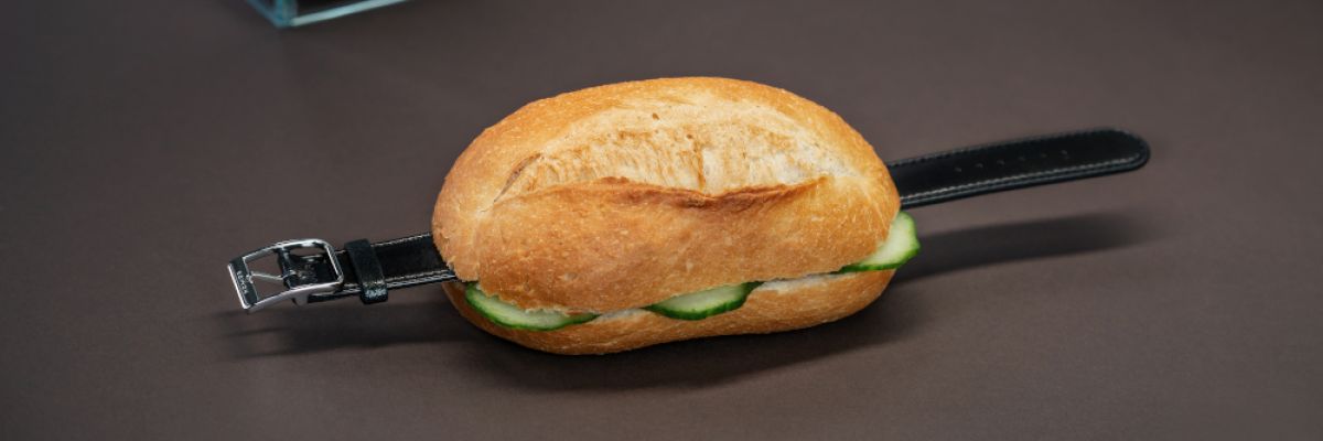 Mit Gürkchen garniert: Diebesgut zwischen Brötchenhälften. Eine Armbanduhr von NOMOS Glashütte versuchte dieser vermeintliche Kunde mitgehen zu lassen, indem er die Uhr mit einer Schrippe „maskierte“. Der Diebstahlversuch wurde rechtzeitig entdeckt, doch ist er keine Ausnahme: Das schwedisch-schweizerische Künstlerduo Zentralgelb dokumentierte bereits eine ganze Reihe von Delikten dieser Art. 
