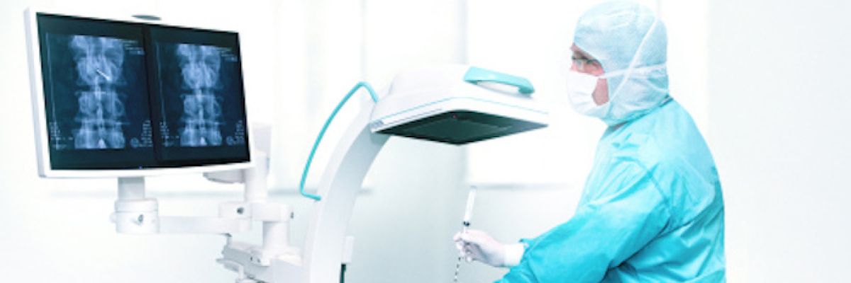 Dr. med. Oliver Wolf (re.) bei einer seiner radiographisch kontrollierten wirbelsäulen-, rückenmarks- bzw. nervennahen Infiltrationen in der Johannesbad Fachklinik Bad Füssing. Diese hochtechnisierte Behandlung wird bereits seit Jahren stationär durchgeführt und kommt ab sofort auch ambulanten Schmerzpatienten zugute ©Johannesbad Gruppe
