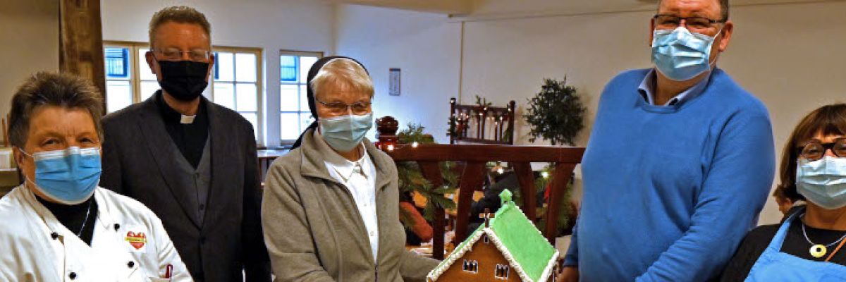 Dompropst Msgr. Joachim Göbel (2.v.l.) übergab die Lebkuchen-Kapelle im Gasthaus an Köchin Helena Hoffmann, Schwester Thoma, Andreas Weber und Beate Kaminski-Stocker vom Gasthaus in der Heierstraße.  ©Ronald Pfaff/ Erzbistum Paderborn