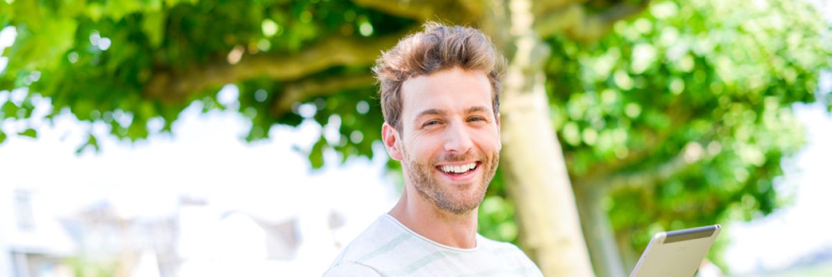 Mann draußen mit Notebook.